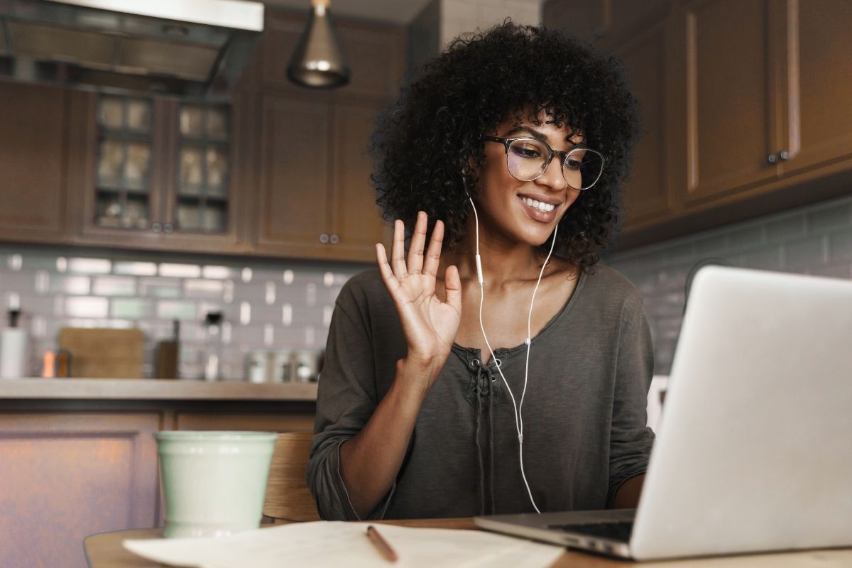 Nonprofit Training Regulations in SA A volunteer secretary smiles and waves as she attends an online meeting from her kitchen, discussing nonprofit training regulations.